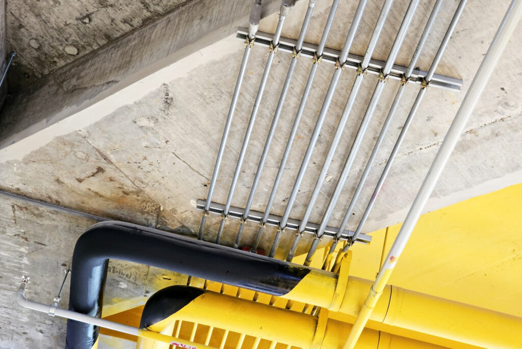 electric metal pipe on raw and yellow concrete ceiling.